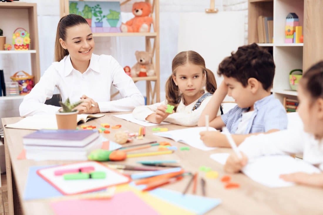 A teacher working at the table with children at Guiding Light Christian Montessori